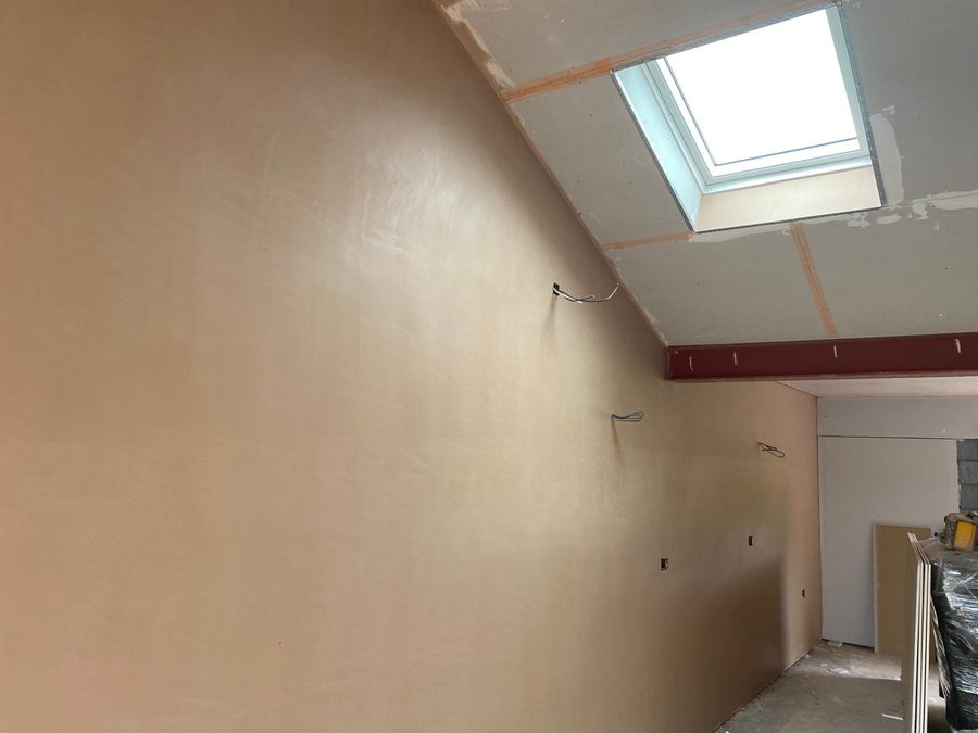 Freshly skimmed wall and vaulted ceiling with a rooflight, wet plaster still pink